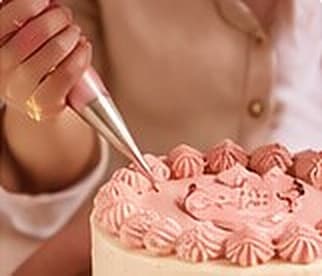 Manos decorando una torta con manga pastelera